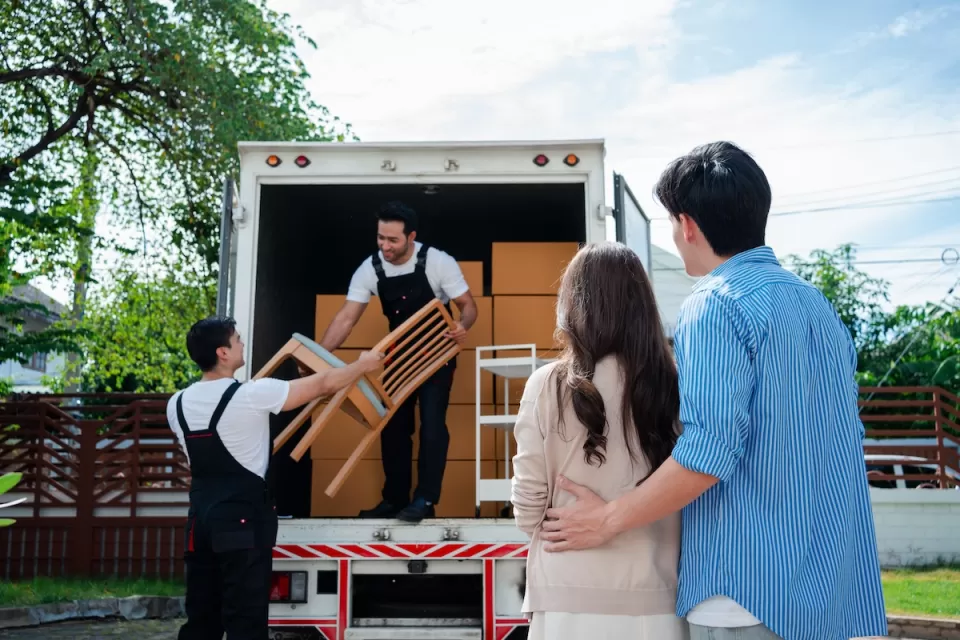 Couple watches as two movers loan furniture into back of box truck.